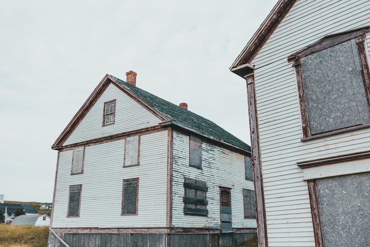 Rustic view of abandoned wooden houses with boarded windows, depicting decay and abandonment.