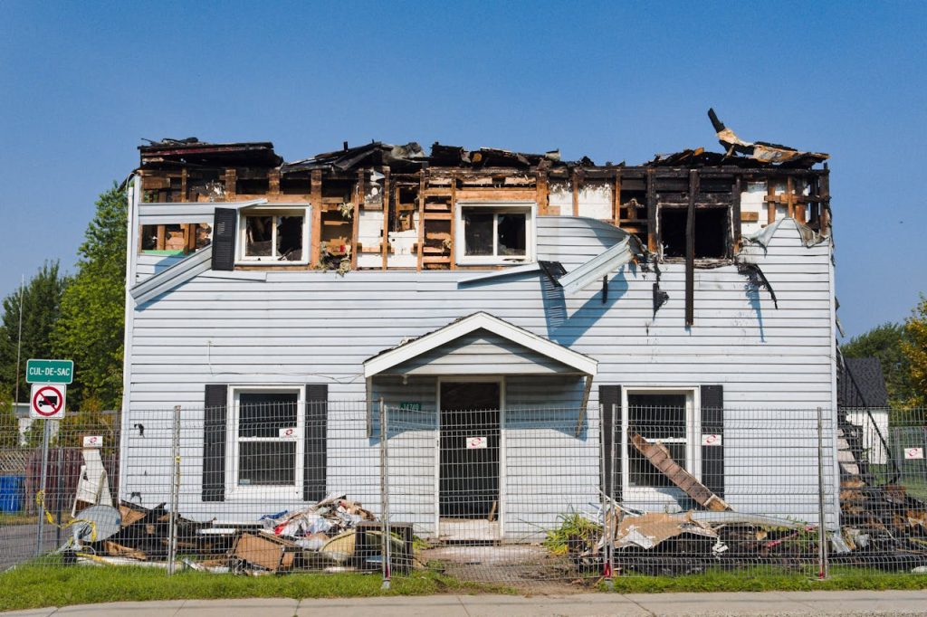 destroyed-house-in-village-17931269 A damaged house with a burnt roof in Bécancour, Quebec, surrounded by a fence.